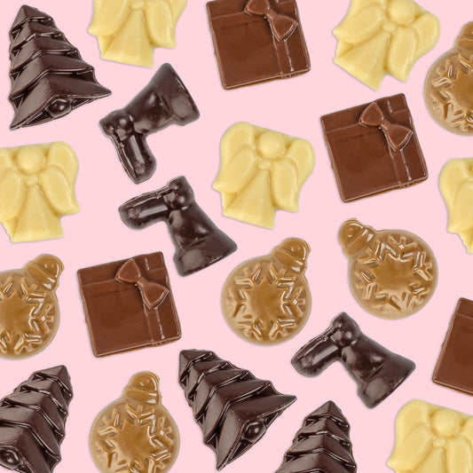 A spread of Hill St. Christmas chocolate shapes in dark, milk, caramel and white chocolate on pink