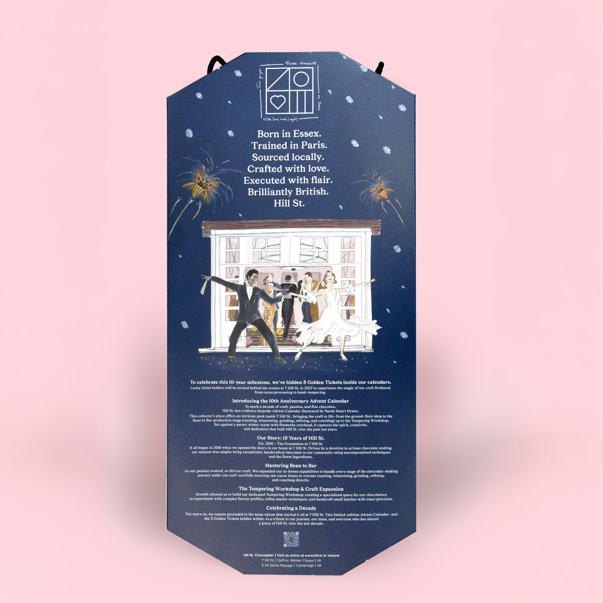 A tall, narrow hanging card or poster with a dark navy blue background, featuring white text, a small logo at the top, and an illustrated scene of a wedding couple in front of a window with fireworks above. The card is photographed against a soft light pink background.